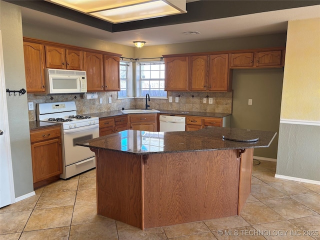 kitchen with white appliances, tasteful backsplash, brown cabinets, and a sink