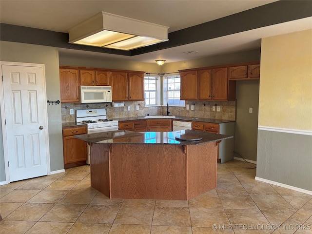 kitchen with a center island, decorative backsplash, brown cabinetry, a sink, and white appliances