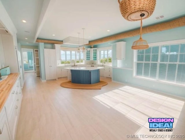 kitchen featuring recessed lighting, light countertops, visible vents, white cabinets, and a kitchen island