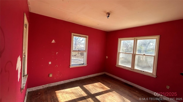 empty room with hardwood / wood-style flooring and plenty of natural light