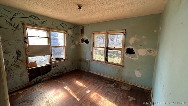 empty room with dark wood-type flooring and a textured ceiling