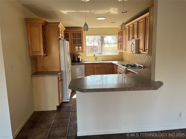 kitchen with sink, hanging light fixtures, kitchen peninsula, white appliances, and decorative backsplash