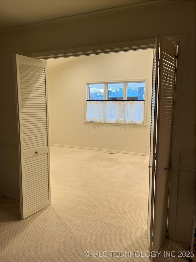 interior space with light colored carpet, ornamental molding, and a closet