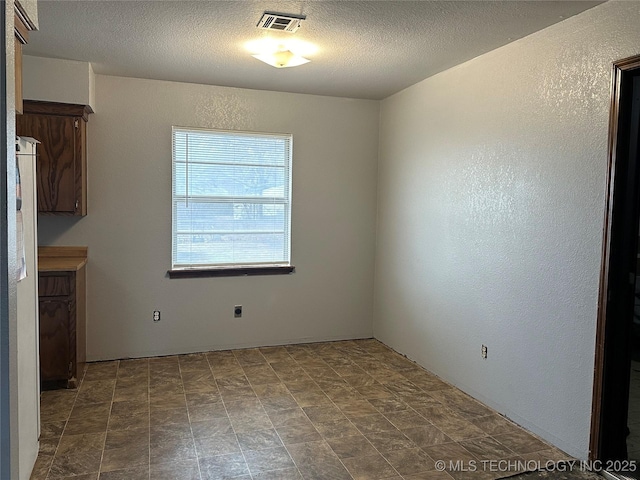 unfurnished dining area with a textured ceiling