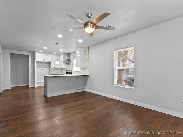 kitchen with wall chimney range hood, a breakfast bar, white cabinetry, hanging light fixtures, and kitchen peninsula