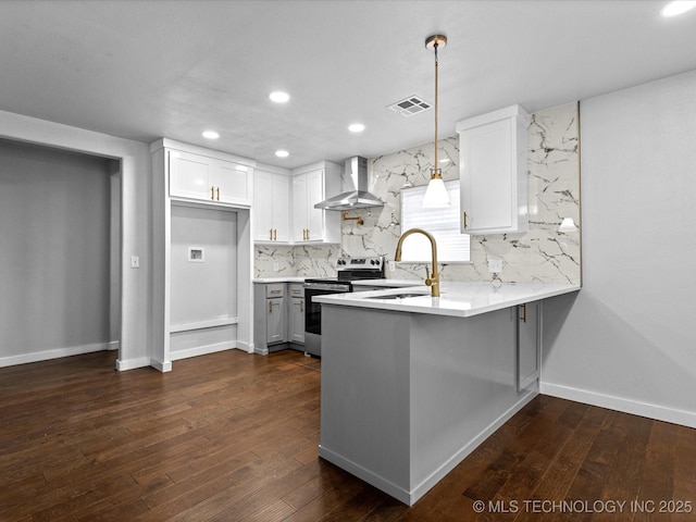 kitchen with pendant lighting, white cabinetry, tasteful backsplash, electric stove, and wall chimney range hood