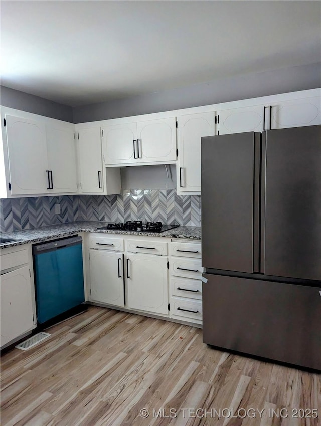 kitchen with white cabinetry, decorative backsplash, light stone counters, black appliances, and light wood-type flooring