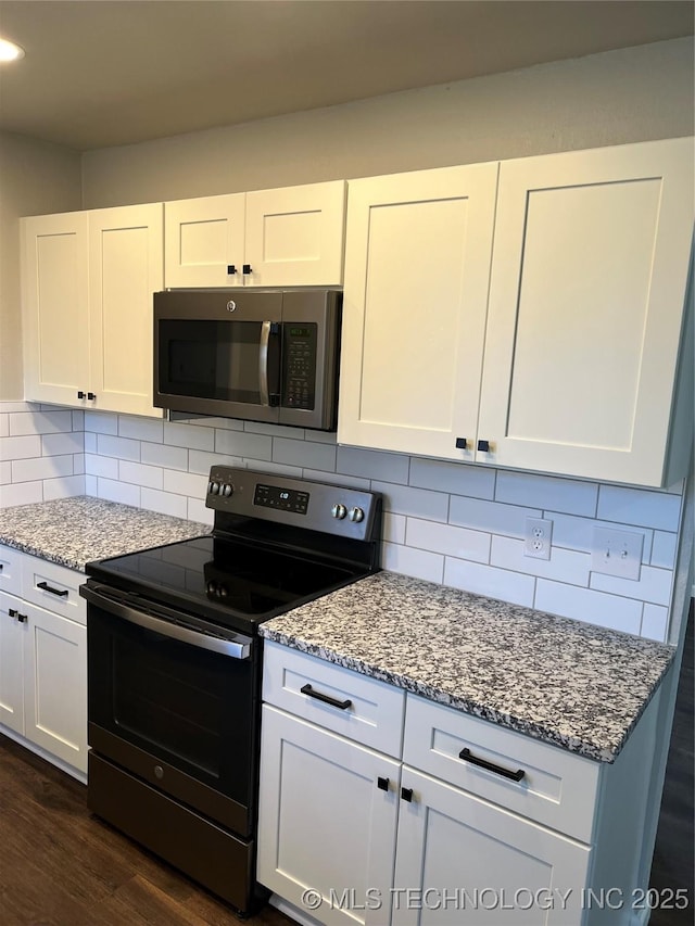 kitchen with white cabinetry, light stone counters, dark hardwood / wood-style flooring, stainless steel appliances, and backsplash