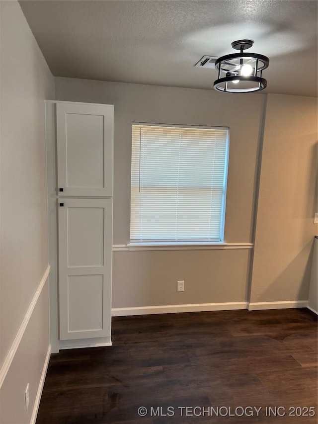 unfurnished dining area featuring dark hardwood / wood-style flooring and a textured ceiling