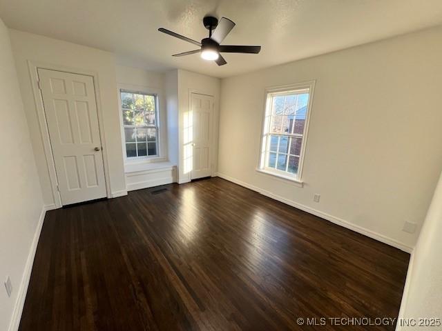 unfurnished room with ceiling fan, plenty of natural light, and dark hardwood / wood-style floors