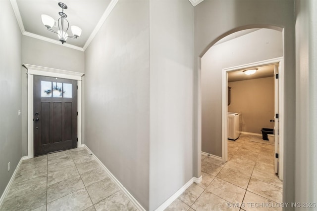 foyer featuring ornamental molding, washer / dryer, light tile patterned floors, and an inviting chandelier