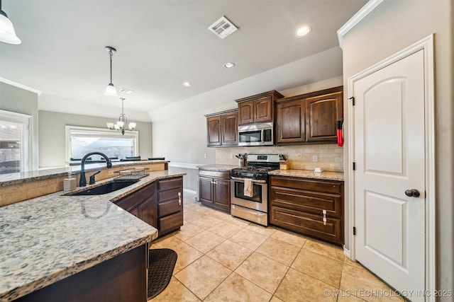 kitchen with sink, decorative light fixtures, light stone countertops, and appliances with stainless steel finishes