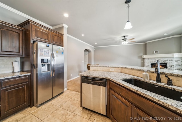 kitchen with sink, decorative backsplash, stainless steel appliances, light stone countertops, and dark brown cabinets