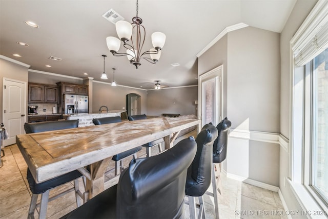 kitchen featuring pendant lighting, ornamental molding, kitchen peninsula, stainless steel refrigerator with ice dispenser, and dark brown cabinets