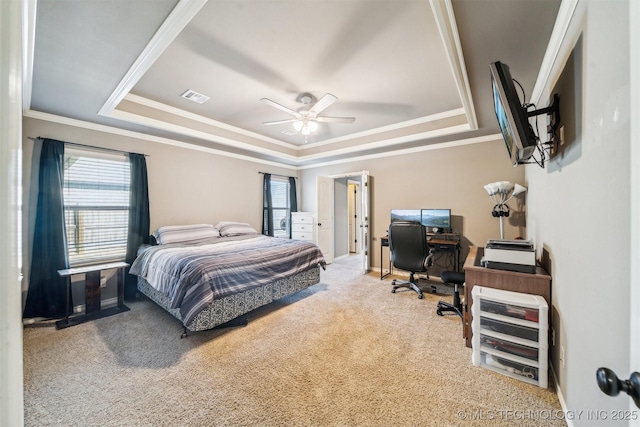 carpeted bedroom with a tray ceiling, ornamental molding, and ceiling fan