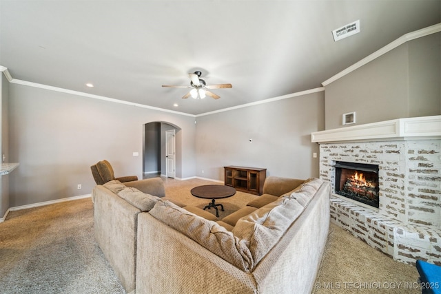 carpeted living room featuring ceiling fan, ornamental molding, and a fireplace