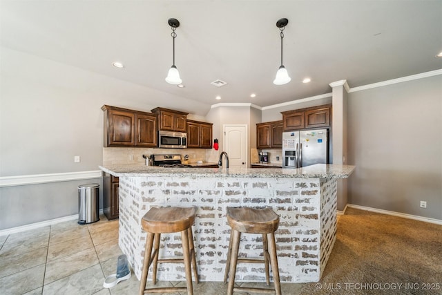 kitchen with appliances with stainless steel finishes, a breakfast bar, light stone counters, and a spacious island