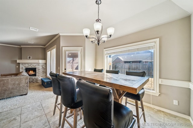 dining area with crown molding, a chandelier, a fireplace, and light tile patterned floors