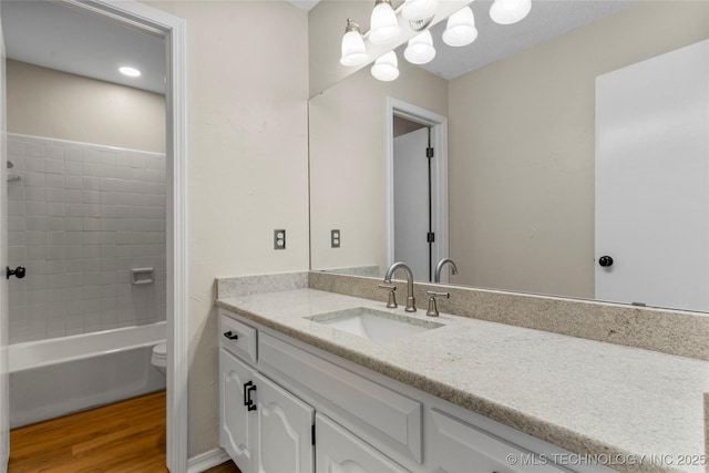 full bathroom featuring hardwood / wood-style flooring, vanity, tiled shower / bath combo, and toilet