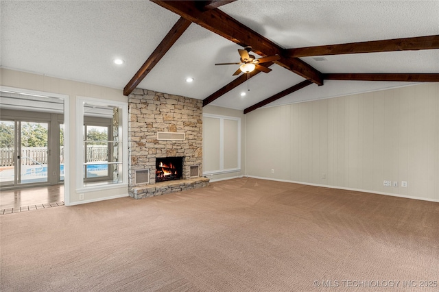 unfurnished living room with vaulted ceiling with beams, a stone fireplace, carpet floors, and a textured ceiling