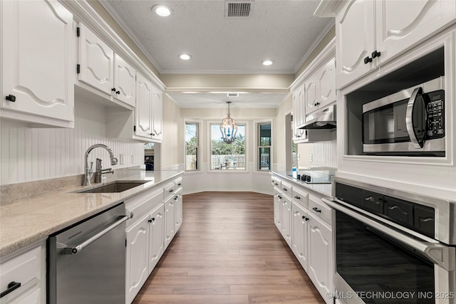 kitchen with dark wood-type flooring, sink, white cabinetry, decorative light fixtures, and appliances with stainless steel finishes