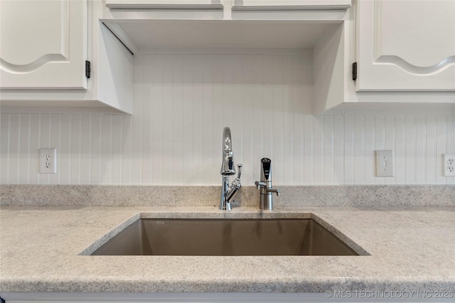 kitchen featuring white cabinetry, sink, decorative backsplash, and light stone countertops