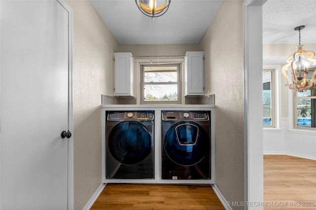 clothes washing area with separate washer and dryer, a chandelier, cabinets, light hardwood / wood-style floors, and a textured ceiling