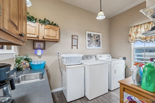 clothes washing area with cabinets, sink, light hardwood / wood-style floors, and washer and dryer