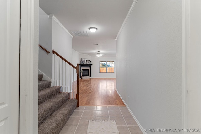 corridor with crown molding and light tile patterned floors