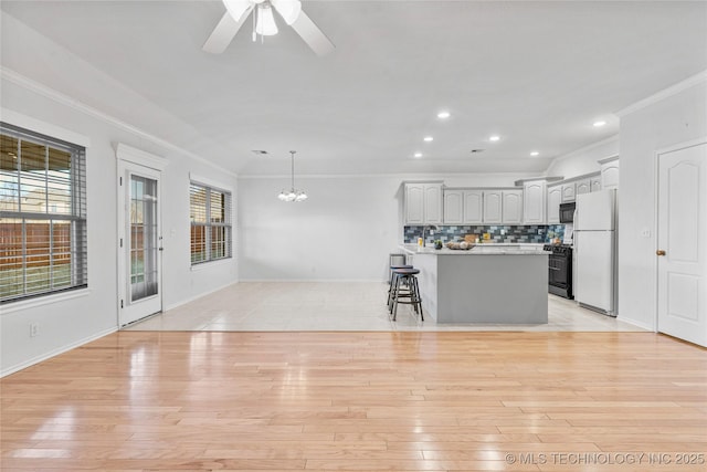 kitchen with gray cabinets, light hardwood / wood-style flooring, a kitchen breakfast bar, tasteful backsplash, and white fridge