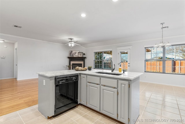 kitchen with ceiling fan with notable chandelier, an island with sink, black dishwasher, sink, and hanging light fixtures