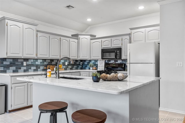 kitchen with tasteful backsplash, an island with sink, sink, and black appliances