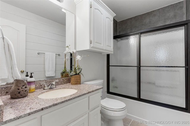 full bathroom with enclosed tub / shower combo, vanity, tile patterned floors, and toilet