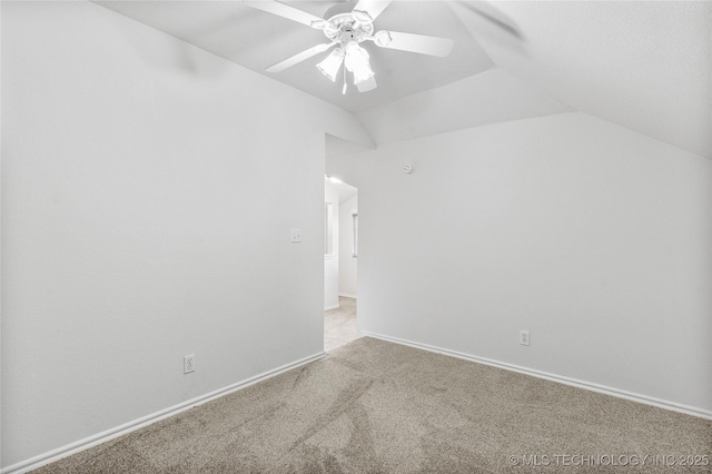 carpeted spare room featuring vaulted ceiling and ceiling fan