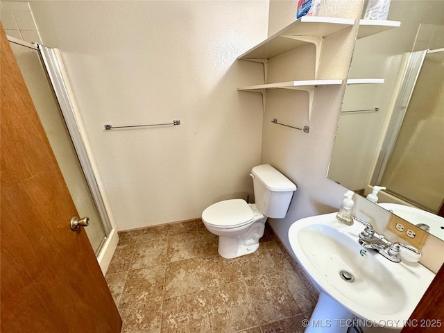 bathroom with sink, an enclosed shower, and toilet