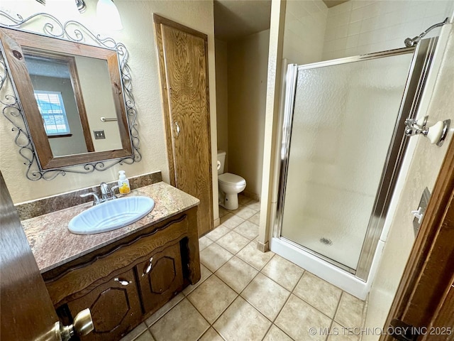 bathroom featuring vanity, a shower with shower door, tile patterned floors, and toilet