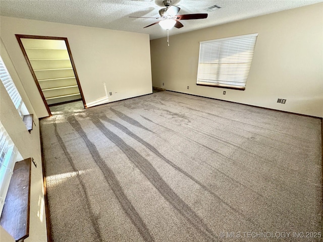 carpeted empty room with ceiling fan and a textured ceiling