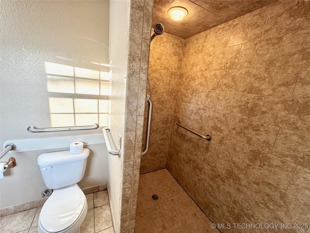 bathroom featuring tiled shower, toilet, and tile patterned flooring