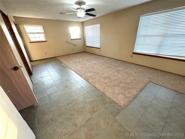 carpeted spare room featuring a textured ceiling and ceiling fan