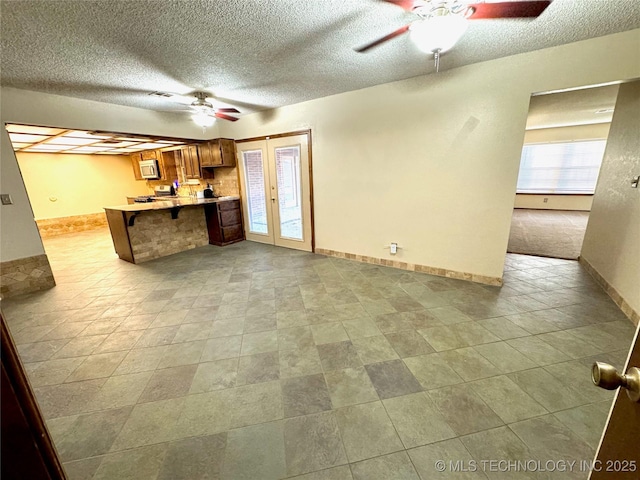 kitchen with a textured ceiling, kitchen peninsula, ceiling fan, and french doors