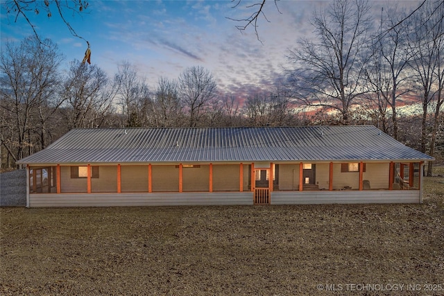 back house at dusk featuring a lawn