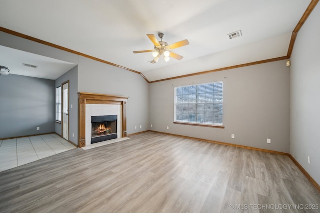 unfurnished living room featuring a tile fireplace, ornamental molding, ceiling fan, and light hardwood / wood-style floors