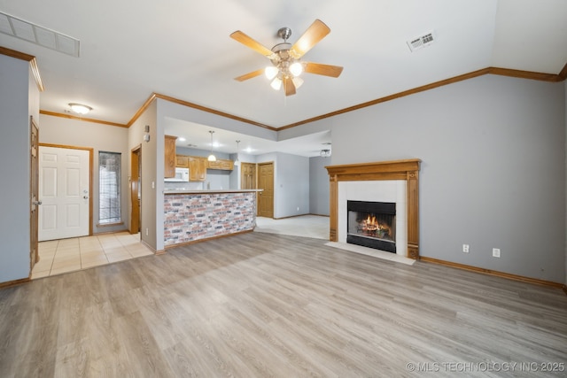 unfurnished living room with a tile fireplace, lofted ceiling, ornamental molding, ceiling fan, and light hardwood / wood-style floors