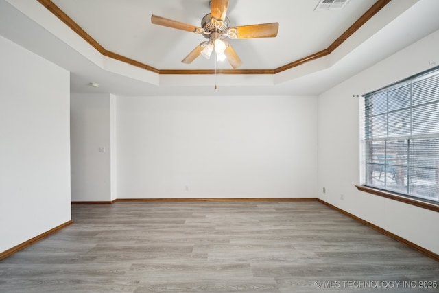 spare room with a raised ceiling, ornamental molding, and light hardwood / wood-style floors