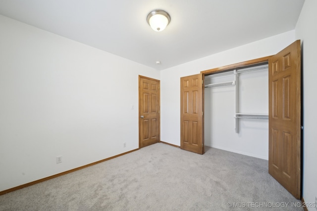 unfurnished bedroom featuring light carpet and a closet