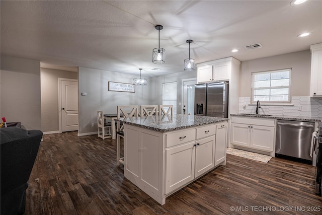 kitchen with sink, white cabinetry, a center island, hanging light fixtures, and appliances with stainless steel finishes