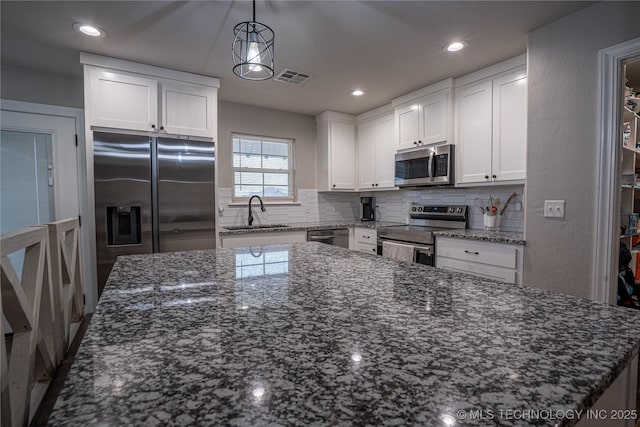 kitchen with decorative light fixtures, sink, white cabinets, dark stone counters, and stainless steel appliances