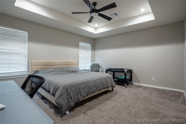 carpeted bedroom featuring a raised ceiling and ceiling fan