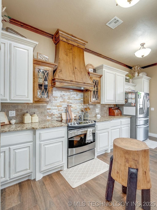 kitchen featuring white cabinetry, decorative backsplash, custom exhaust hood, and stainless steel appliances