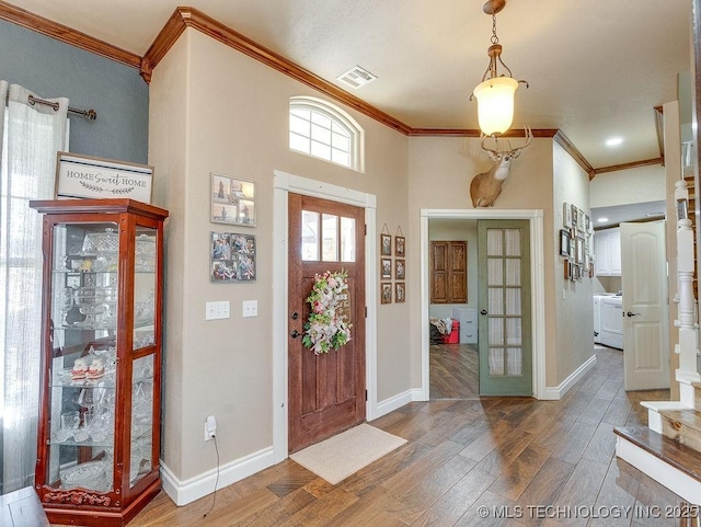 foyer entrance featuring crown molding, washer / dryer, and hardwood / wood-style flooring